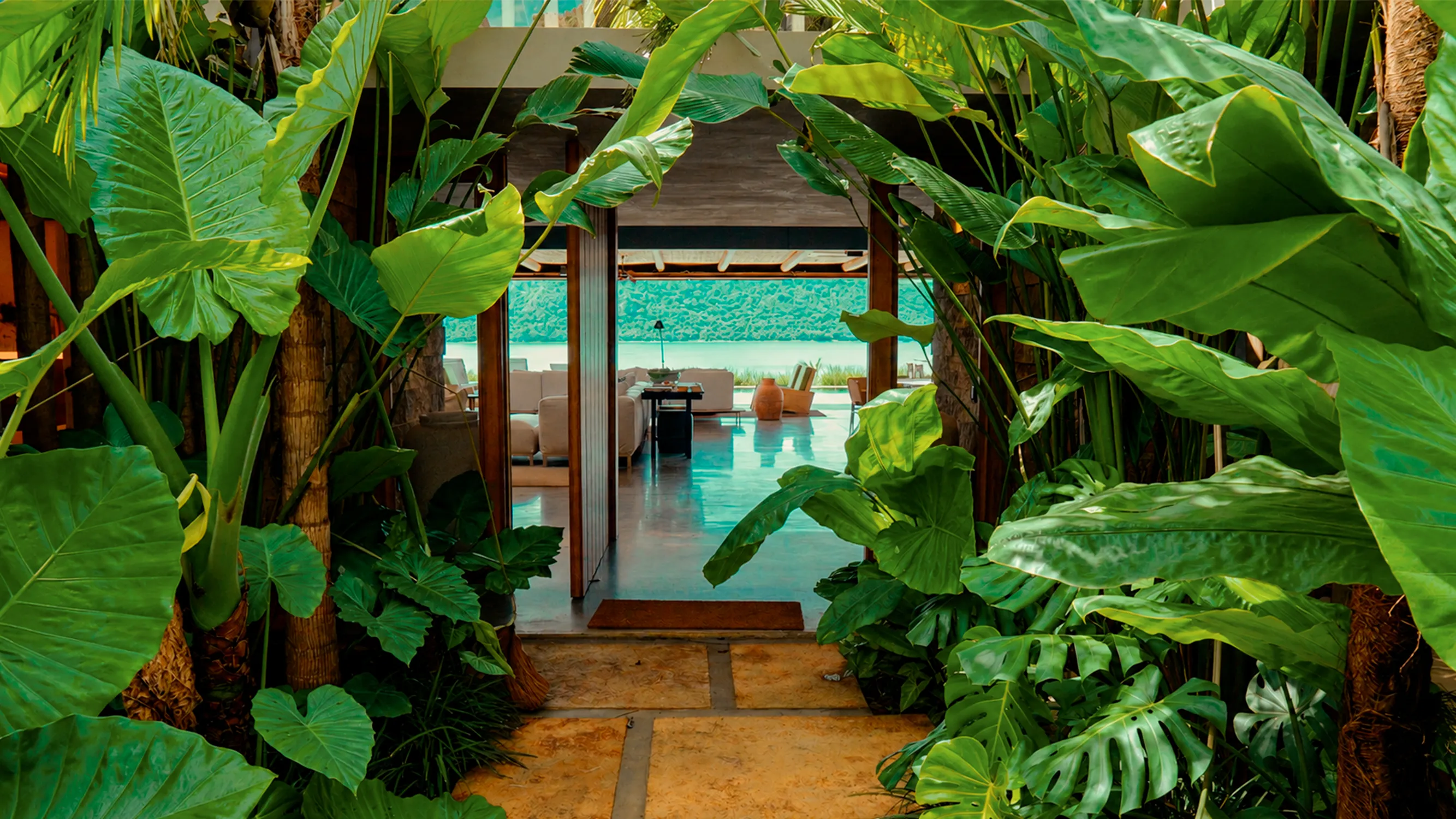 Entrada da residência com paisagismo verde e corredor