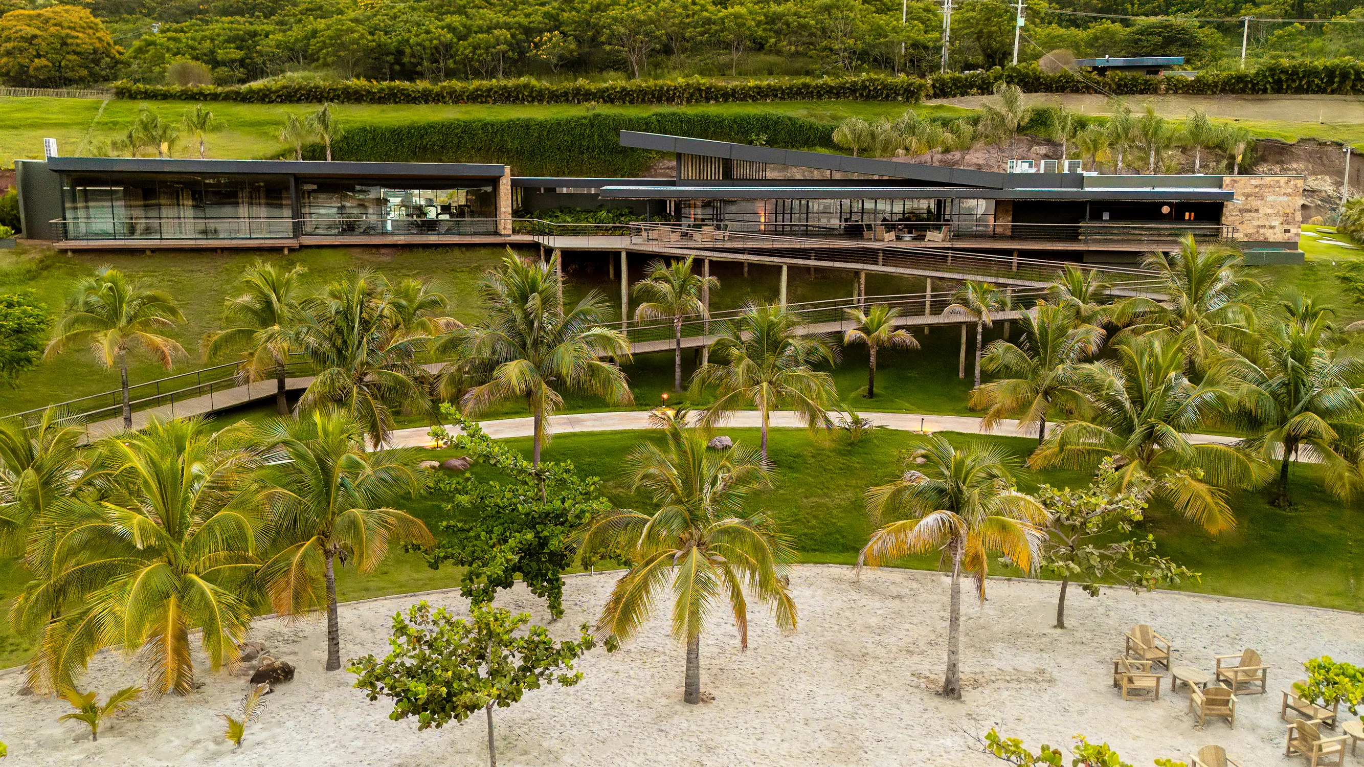 Vista aérea do espaço gourmet com coqueiros, jardins e a praia à frente